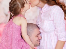 Valokuvan kuvaus raskaana olevasta naisesta miehensä ja lapsensa kanssa studiossa