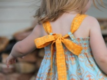 Binden von Trägern an einem Kleid für ein Mädchen