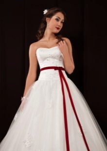 Uzpūtīga kāzu kleita ar zemu jostasvietu un sarkanu jostu