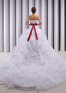 Un magnífico vestido de novia con un tren y un lazo rojo.