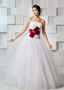 Un magnífico vestido de novia con un lazo rojo.