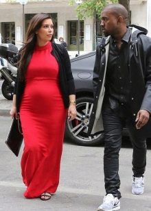 Vestido largo de maternidad rojo con un cárdigan negro y un bolso negro