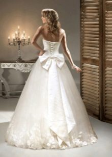 Un vestido de novia con un lazo y flores en tono.