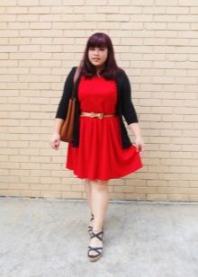 Vestito rosso lavorato a maglia per una ragazza piena con una cintura dorata, un cardigan nero e sandali