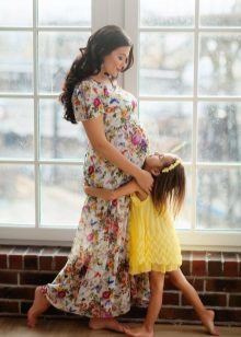 Valokuvan kuvaus raskaana olevalle naiselle pitkässä mekossa, kukkakuvalla
