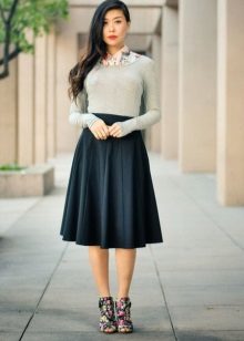 Falda cónica de longitud media combinada con una blusa gris.