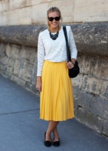 Een gele rok onder de knie in combinatie met een witte blouse