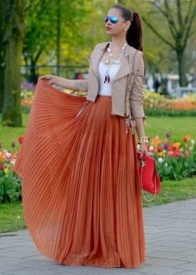 Uma saia longa com sol no chão combinada com uma jaqueta de couro