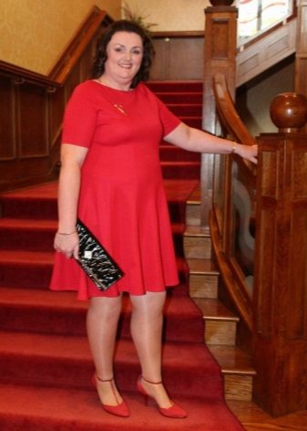 Punainen mekko ylipainoisille naisille, punaisilla kengillä ja mustalla kytkimellä